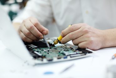 Closeup shot of male hands  working on disassembled laptop with screwdriver and tweezers looking for broken pats